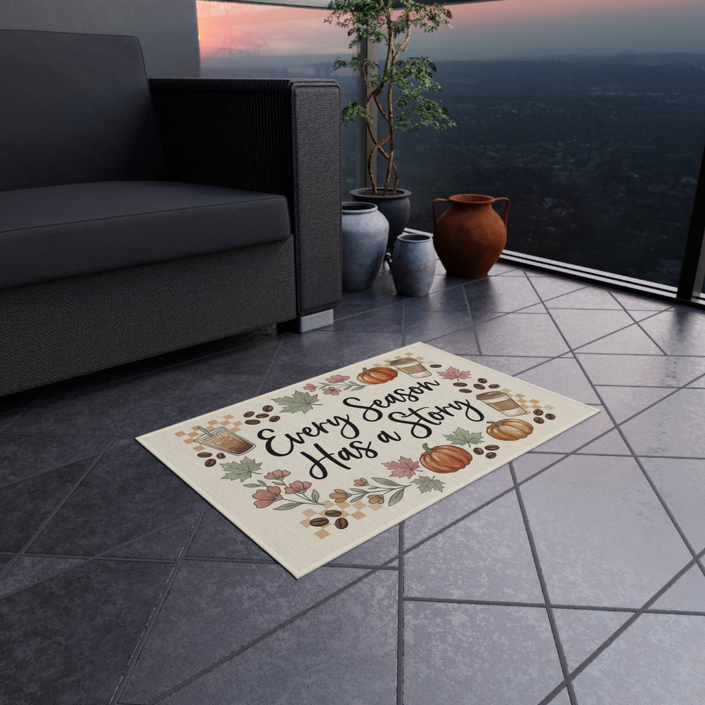 Every Season Has a Story Outdoor Rug, a fall doormat with pumpkins, leaves, and coffee cups, on a patio.
