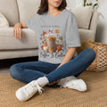 Model wearing a gray "Leaves Are Falling... Coffee Is Calling" t-shirt with an iced latte, pumpkins, and fall leaves graphic, front view.