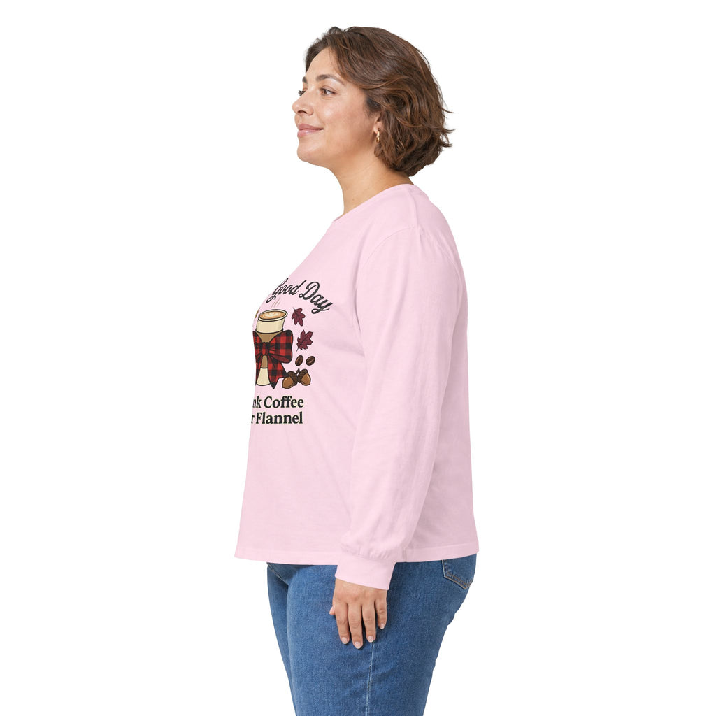 Side view of a woman wearing a light pink long sleeve tee with a coffee cup and fall leaves graphic.