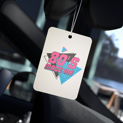 80's Made Me Car Air Freshener, rectangular, hanging from a rearview mirror, with pink and teal retro graphic.