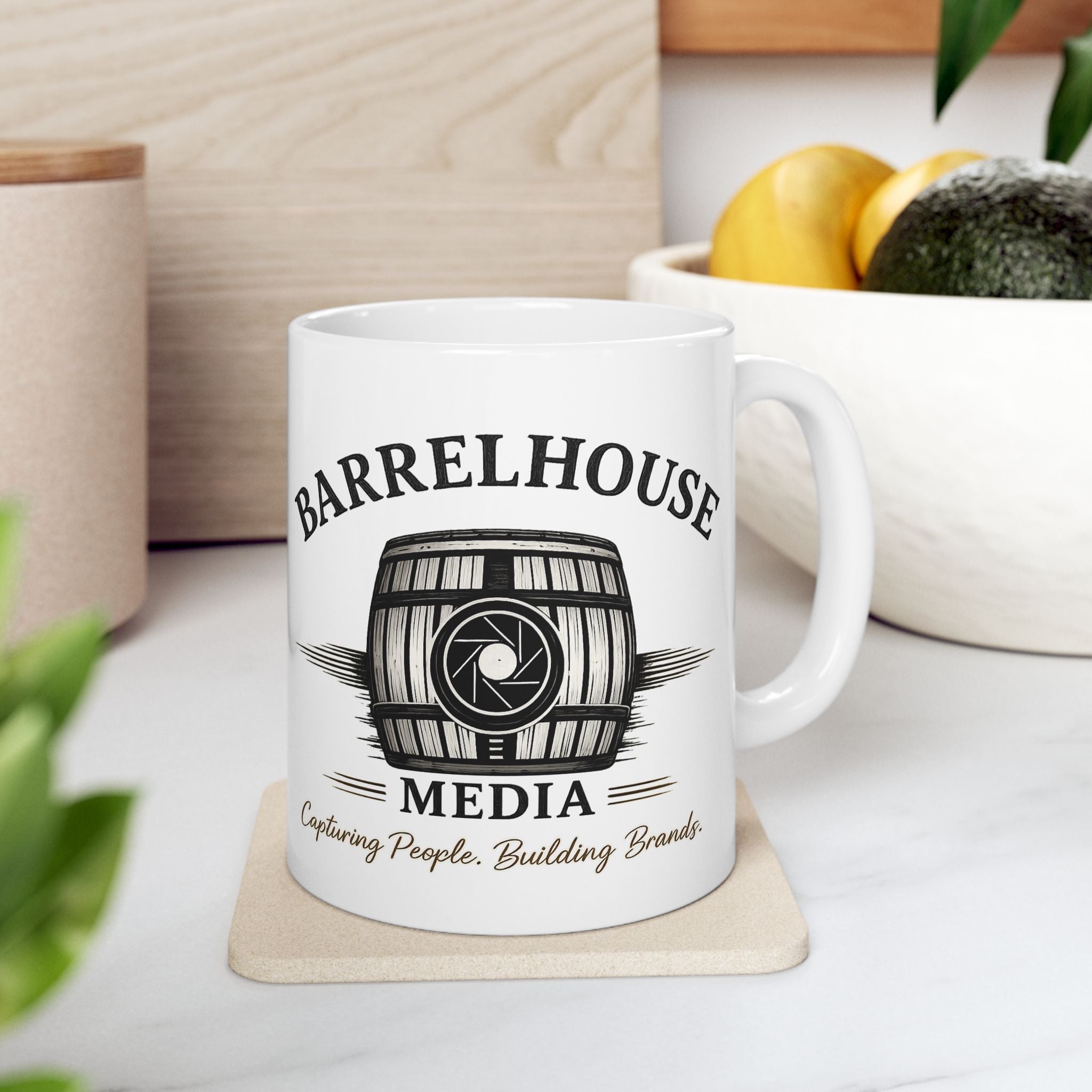 Front view of a white ceramic Barrelhouse Media Logo Coffee Mug with a barrel and camera lens graphic.