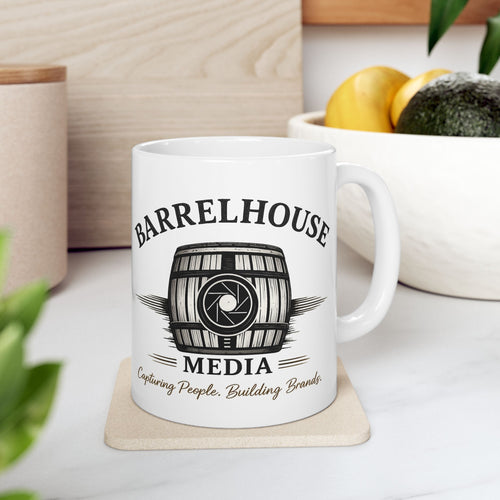Front view of a white ceramic Barrelhouse Media Logo Coffee Mug with a barrel and camera lens graphic.