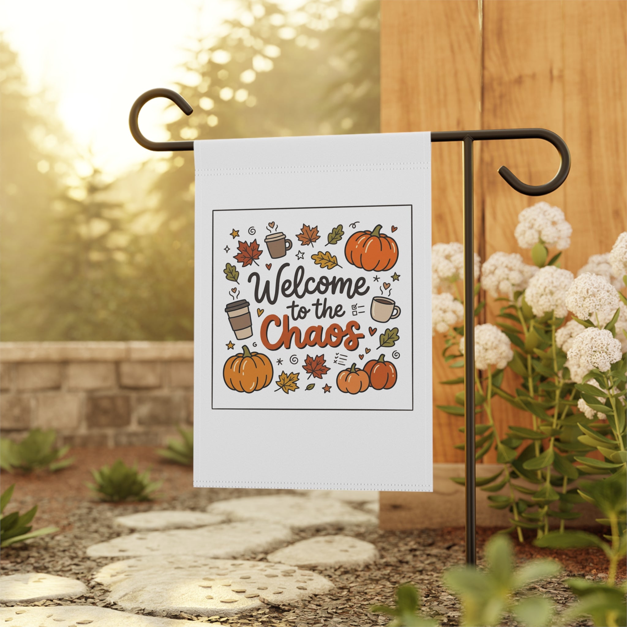 Welcome to the Chaos Fall Garden Flag with pumpkins, coffee cups, and autumn leaves, hanging on a garden stand.